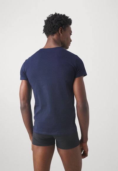 Marineblå t-skjorte med korte ermer i bomull, tettsittende design, rund hals, jevn tekstur, brukt sammen med svarte shortser, bakperspektiv.