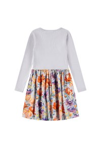 Robe à manches longues avec un haut côtelé blanc et une jupe évasée à motifs floraux dans des teintes d'orange, de violet et de jaune sur un fond clair.