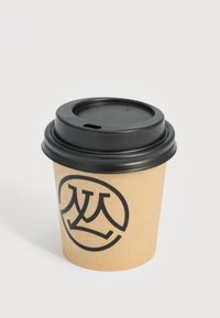 Vaso desechable de café marrón con tapa de plástico negra y un logotipo circular negro con letras estilizadas superpuestas en el lateral.