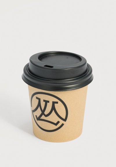 Καφέ χάρτινο ποτήρι καφέ μιας χρήσης με μαύρο πλαστικό καπάκι και έναν κυκλικό μαύρο λογότυπο με στυλιζαρισμένα επικαλυπτόμενα γράμματα στην πλευρά.
