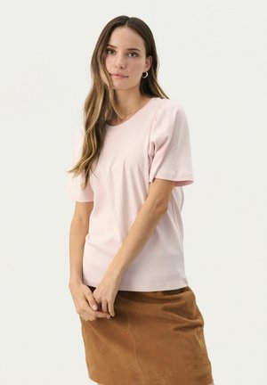 Helles rosa T-Shirt mit kurzen Ärmeln und Rundhalsausschnitt, kombiniert mit einem braunen Rock aus weichem, strukturiertem Stoff.