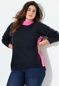 Pull bleu marine avec un col rose et des panneaux latéraux, manches et ourlet côtelés. Texture douce, coupe décontractée et fentes latérales pour plus de confort.