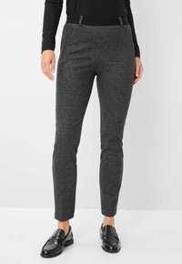 Grijze textuurbroek met een slim fit, voorzien van een zwarte tailleband en een subtiel patroon, gecombineerd met zwarte loafers.