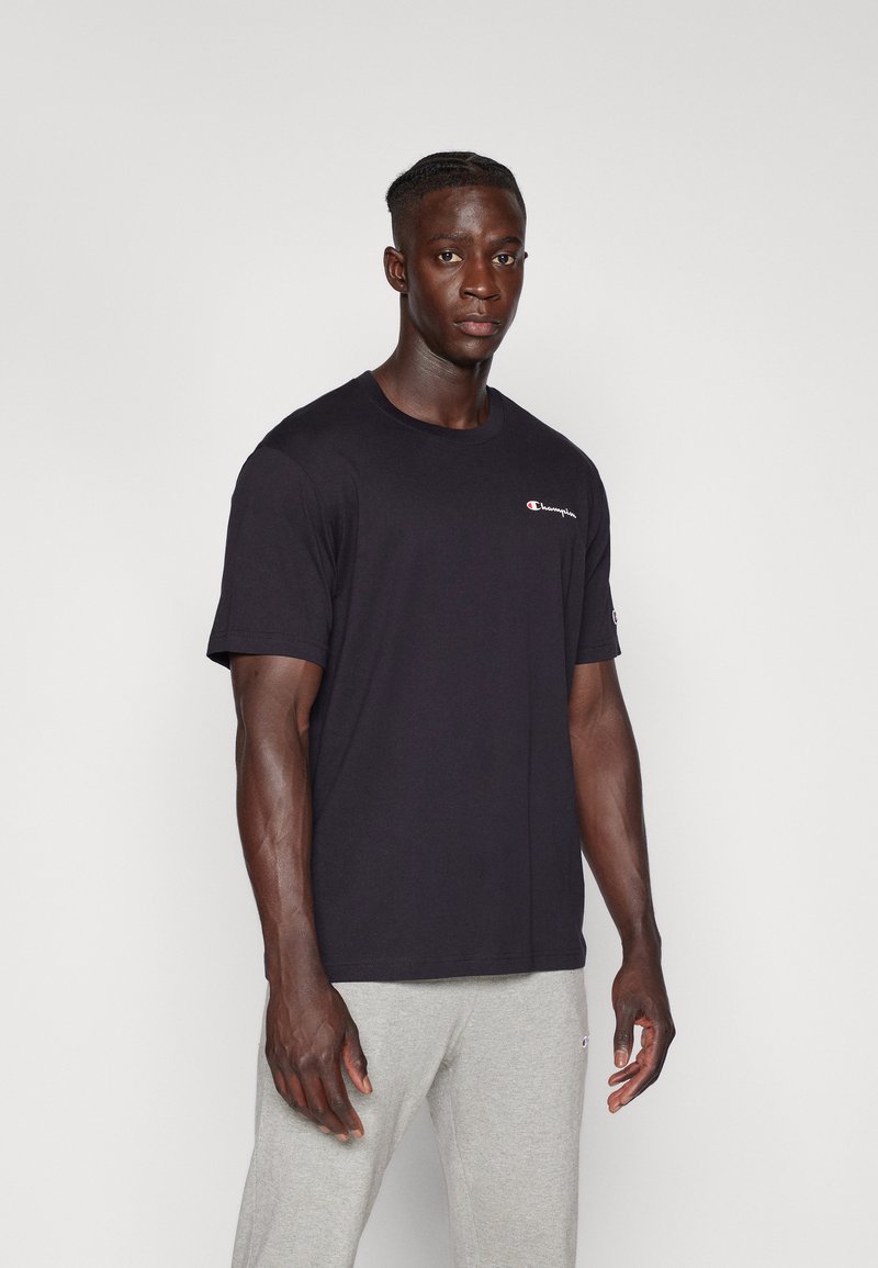Sort bomulds T-shirt med rund hals og korte ærmer, med et lille rødt og hvidt logo på brystet og ærmet.