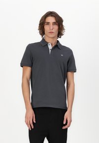 Mørk grå polo-skjorte med korte ermer, med en kontrasterende lys grå krage, tre knapper og en logo på brystet.