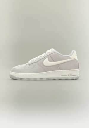 Sneaker bassa in camoscio grigio chiaro con swoosh Nike bianco, lacci bianchi e suola ammortizzata con la scritta "AIR" sul tallone.