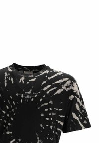 Černé tričko s krátkým rukávem a barevným vzorem v duhových odstínech, s bílými radiálními vzory a malým bílým textem potištěným na hrudi pod výstřihem.