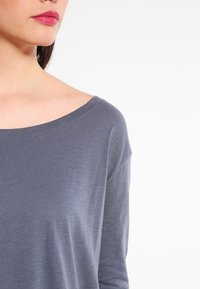 Grå långärmad tröja med en bred, rund halsringning. Mjuk textur och avslappnad passform. Inga synliga mönster eller hårdvarudetaljer.