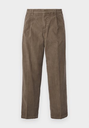 Calças de veludo cotelê castanhas com um corte relaxado, apresentando riscas verticais visíveis, bolsos laterais e uma cintura com passantes para cinto.