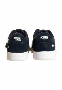 Scarpe sintetiche blu navy con suola in gomma bianca, caratterizzate da un retro testurizzato, dettagli cuciti e un logo sul tallone.