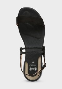 Svart platt sandal med ett mjukt mockaband och elastiska band, med en texturerad svart sula och en krämfärgad fotbädd. Storlek 36.