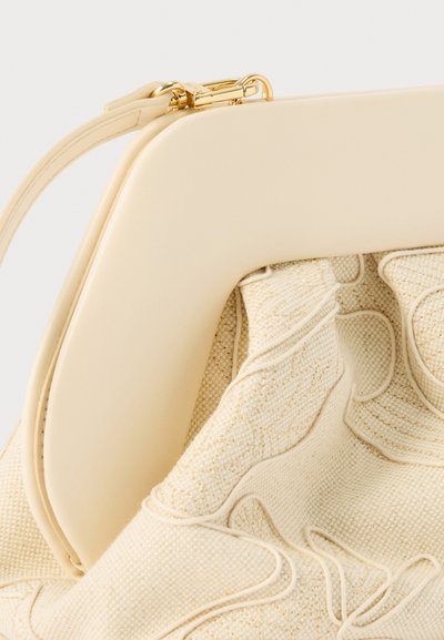 Τσάντα χειρός σε κρεμ απόχρωση με λεία κορνίζα και σώμα από υφασμάτινη υφή που διαθέτει ανάγλυφη κυματιστή ραφή και χρυσό κούμπωμα στο λουρί.