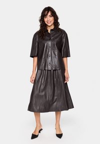 Black leather top with short sleeves and buttons, paired with a matching black leather skirt. Smooth texture and sleek design.