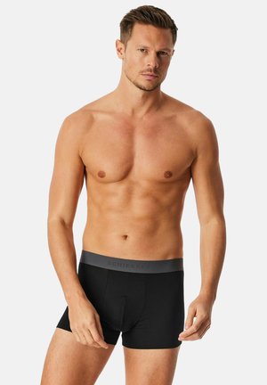 Schwarze Boxershorts aus Stretchstoff mit einem grauen Bund, der die Marke "Schiesser" in dezenter Schrift trägt.