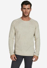 Beige gestrickter Pullover mit langen Ärmeln, Rundhalsausschnitt und Raglanärmeln, der einen strukturierten Stoff und ein dezentes Muster aufweist.