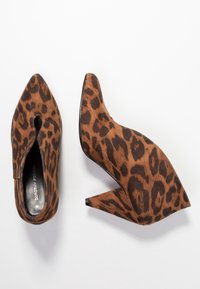 Leopardenmuster High-Heels in Braun und Schwarz, mit spitzer Zehe und Wedge-Absatz, aus einem weichen, strukturierten Obermaterial.