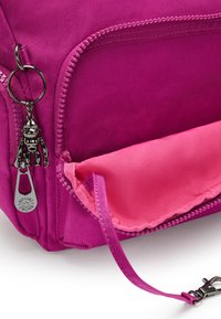 Borsa rosa porpora con una texture liscia, dotata di una chiusura a zip e di un portachiavi con un charm di scimmia metallico. Fodera interna in satin rosa.