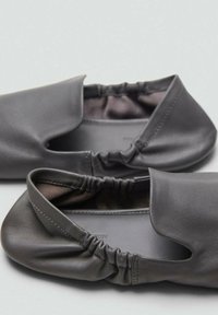 Miękkie, ciemnoszare skórzane baleriny z elastycznymi otworami i zaokrąglonymi czubkami, umieszczone na neutralnej powierzchni.