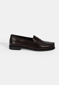 Bruine leren loafers met een gladde afwerking, voorzien van decoratieve stiksel langs de bovenkant en een platte zwarte rubberen zool.