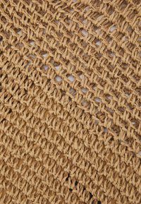 Woven straw mat o naturalnym brązowym kolorze, z otwartym wzorem siatki i splecioną teksturą, z drobnymi różnicami w gęstości tkania.