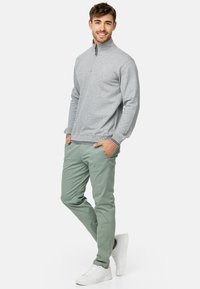 Szary polarowy sweter z pół-zamkiem, ribbowane mankiety, w połączeniu z jasnoszarymi chinosami i białymi sneakerami. Minimalistyczny design i miękka tekstura.