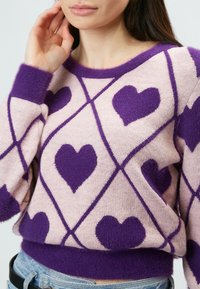Lila, herzgemusterter Pullover aus weichem Stoff, mit einem Rautenmuster, einem runden Ausschnitt und gerippten Bündchen.