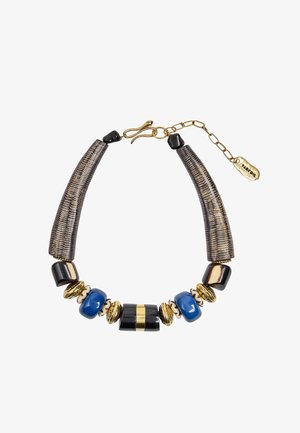 Gruby naszyjnik z dużych złotych, czarnych, niebieskich i kremowych koralików, teksturowanych ciemnych zakrzywionych segmentów oraz złotego zapięcia na łańcuszku z małą metką.