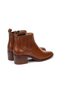 Bottines en cuir marron avec un bout pointu, un talon empilé et des panneaux latéraux élastiques avec des coutures verticales. Petit logo appliqué sur le côté.