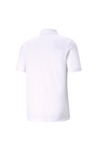 Vit polo skjorta gjord av mjukt, andningsbart tyg, med nedfällbar krage, korta ärmar och en slät yta utan synliga mönster.