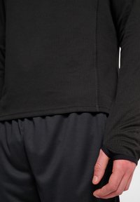 Zwarte langemouwen shirt met een ruitstructuur, ronde halslijn en duimgaten in de mouwen, gecombineerd met zwarte elastische taillebandbroek.