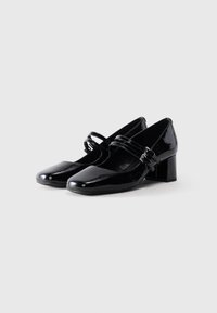 Pair of black patent leather Mary Jane shoes with square toes, double straps, silver buckles, and low block heels on a white background.