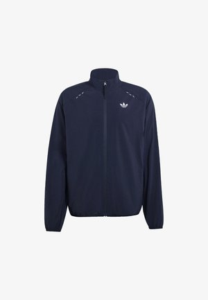 Tummansininen vetoketjullinen urheilutakki pystypäällä, joustavat hihansuut ja helma, Adidas Trefoil -logo vasemmassa rinnassa ja heijastavat saumalaskokset.