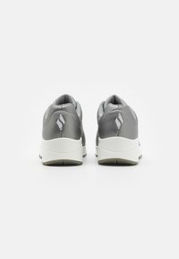 Graue Sportschuhe mit einem eleganten Oberdesign, das eine durchlässige Textur, ein zentrales Logo und eine weiße Gummisohle für besseren Halt aufweist.
