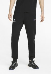 Sorte joggingbukser med BMW Motorsport-logoer, med et tilspidset design, elastiske manchetter og mesh-sidede paneler for åndbarhed.