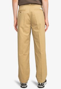 Khaki trousers with a straight cut, featuring back pockets and a label on the waistband, made from a durable cotton blend.