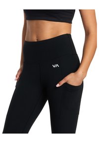 Mustat leggingit, joissa on korkea vyötärö, valmistettu sileästä materiaalista. Sisältää sivutaskun ja pienen valkoisen logon edessä.