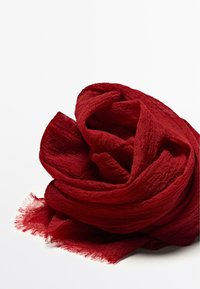 Crinkled deep red scarf with fringed edges, loosely folded against a white background.
