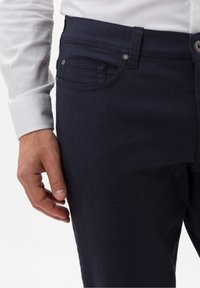 Marinblå bomullsbyxor med en texturerad tyg, klassisk femficksdesign och en subtil kontrastsöm längs sömmarna.