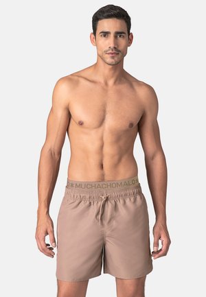 Bruine zwembroek met een elastische tailleband met een logo, gemaakt van lichtgewicht materiaal, ontworpen voor comfort en beweging.