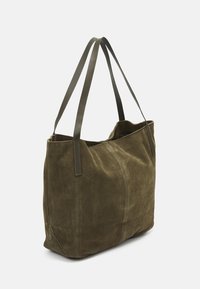 Sac fourre-tout en daim vert olive avec deux longues anses en cuir. Il présente une texture douce et un design minimaliste avec des détails de couture visibles.