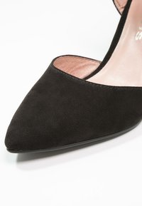 Chaussure plate en daim noir pour femme avec bout pointu, côtés bas et doublure intérieure rose clair.