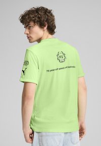 Lys grøn bomulds t-shirt med "F1" logo og tekst på ryggen, med korte ærmer og en almindelig pasform. Ikoniske branddetaljer inkluderet.