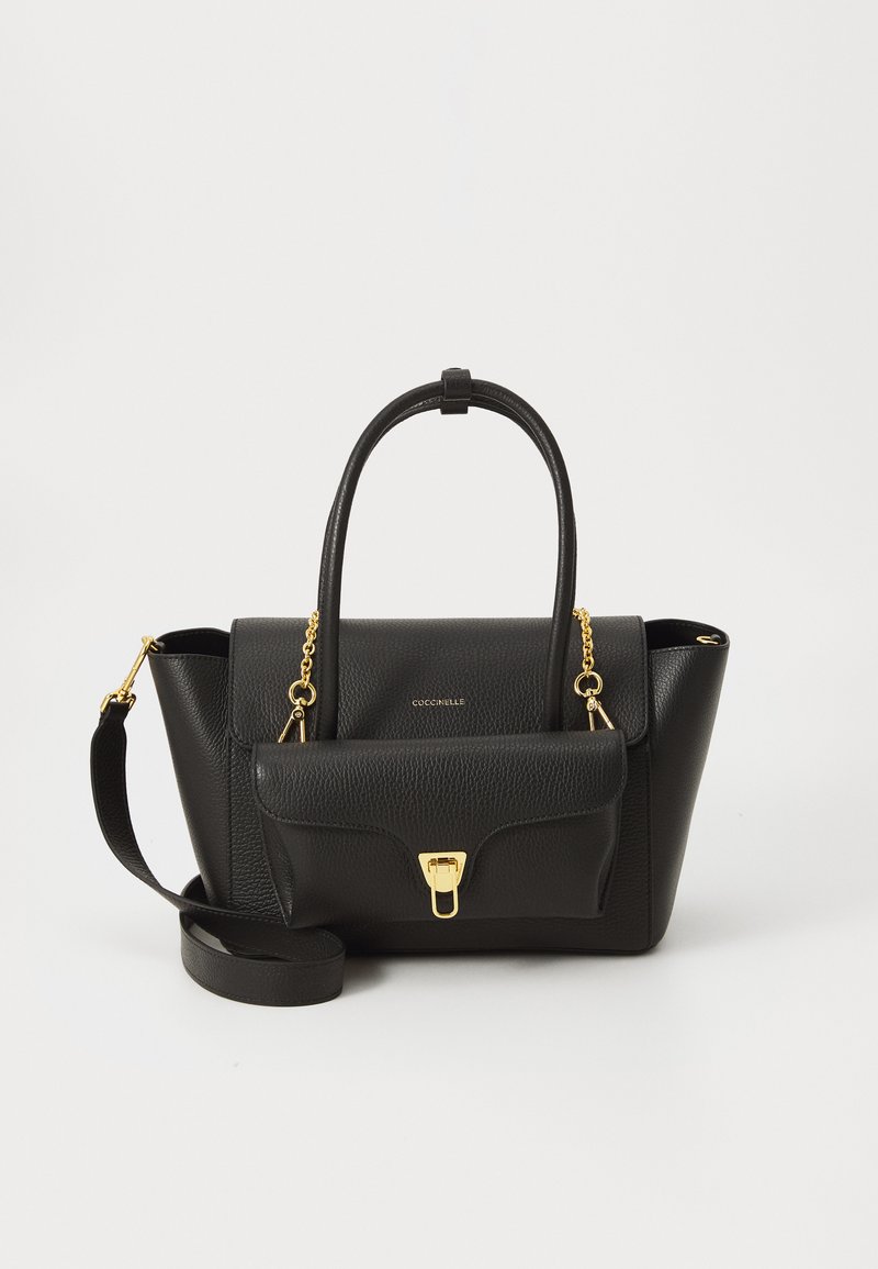 Sac à main en cuir noir avec poignées doubles et une bandoulière amovible, comportant une poche avant fermée par un fermoir doré. Accents en quincaillerie dorée.