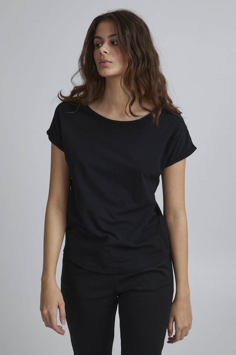 Schwarzes T-Shirt mit kurzen Ärmeln aus weichem Stoff, mit Rundhalsausschnitt und aufgerollten Ärmeln, kombiniert mit schwarzen Hosen. Schlichtes, minimalistisches Design.