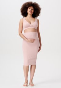 Graviditetsoutfit med en ribbet, lys rosa bralette og matchende midi-nederdel. Sættet har en tætsiddende silhuet og blød tekstur.