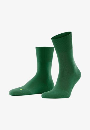 Green socks with a ribbed cuff, a smooth texture, and a lightweight design. Features a small yellow logo on the sole.