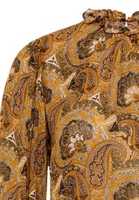 Blouse à manches longues avec un motif paisley en jaune moutarde, marron et blanc. L'encolure présente un détail de volants froncés.
