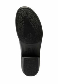 Suela de zapato negro con agarre texturizado y un diseño de insecto grande en relieve, con el nombre de la marca "FLY London" cerca del talón.