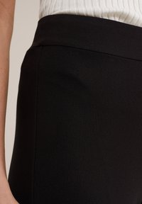 Černá sukně z hladké, texturované tkaniny. Pas je elegantní a sukně má přiléhavý střih, který zdůrazňuje čisté linie.