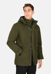 Giacca isolante verde oliva con zip e chiusure a scatto, dotata di due tasche frontali con zip e cappuccio rimovibile. Texture liscia.